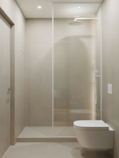 a white toilet sitting next to a shower in a bathroom under a light fixture on the wall