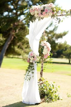 the wedding arch is decorated with pink flowers and greenery for an elegant outdoor ceremony