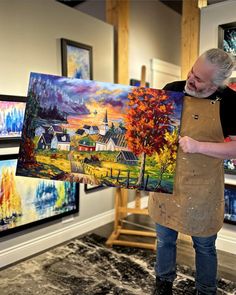 a man holding up a large painting in front of his face and looking at it