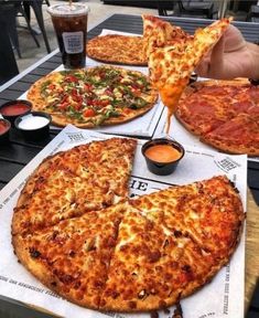 a table topped with lots of pizzas on top of paper napkins and sauce