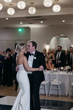 a bride and groom sharing a first dance at their wedding in front of an audience