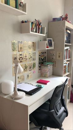 a white desk topped with a laptop computer next to a book shelf filled with books