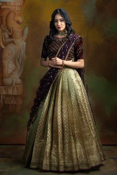 a woman in a purple and gold lehenga is posing for the camera with her hands on her hips