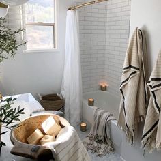 a bathroom with towels hanging on the wall and candles in the bathtub next to it