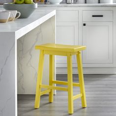 a yellow stool sits in the middle of a kitchen