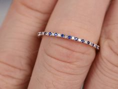 a woman's hand with a diamond and blue sapphire band on her ring finger