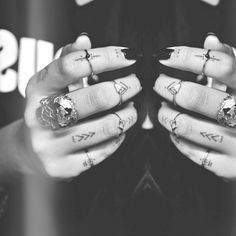 two hands with rings and tattoos on them