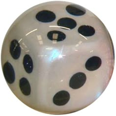 a white and black polka dot ball sitting on top of a wooden table next to a wall