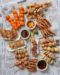 a bunch of food that is laying out on a newspaper with some dipping sauces