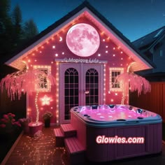 a hot tub in front of a pink house with lights on the roof and trees around it