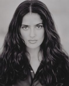 a black and white photo of a woman with long dark hair, looking at the camera