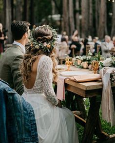 a man and woman sitting at a table with flowers in their hair, surrounded by other people