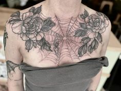 a woman with flowers and spider web on her chest tattooing it's back