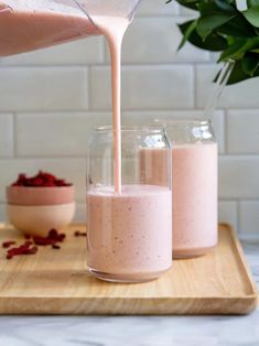 someone pouring pink smoothie into small glass jars