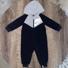 Nike Baby Boy Hooded Jumpsuit / Romper Size 9 Months Please See Pictures For Measurements Color: Black With Light Gray Hood And Chest Area, White Nike Logo On Front And Back Hooded Zips For Easy Changing Long Sleeve 60% Cotton 40% Polyester Exclusive Of Decoration Like New Condition Washed But Never Worn Paid $35.00 May Bundle If You Have Any Questions, Feel Free To Message Me :) Check Out My Page For More I Have A Ton Of Baby Items And Clothes- New, And In Good Condition! Black Hooded Onesie For Loungewear, Casual Black Long Sleeve Onesie, Nike Cotton Onesie For Playwear, Sporty Cotton Long Sleeve Onesie, Sporty Long Sleeve Cotton Onesie, Nike Cotton Onesie For Loungewear, Nike Casual Long Sleeve Onesie, Nike Casual Onesie For Playtime, Casual Nike Onesie For Playtime