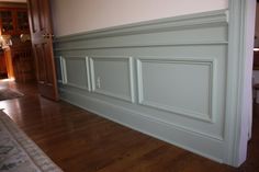 an empty room with wood floors and white paneling on the wall, in front of a doorway