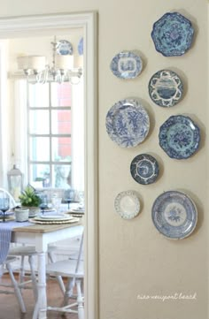 blue and white plates are hanging on the wall next to a dining room table with chairs