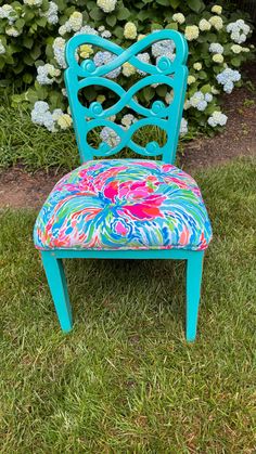 a blue chair sitting on top of a lush green grass covered field next to flowers