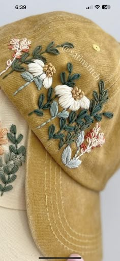 two hats with embroidered flowers on them sitting next to each other