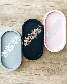 three empty trays sitting on top of a wooden table next to each other,