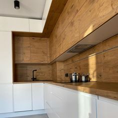 a kitchen with white cabinets and wooden counter tops on the wall, along with pots and pans