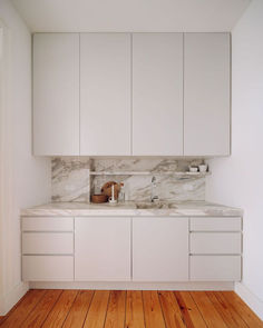 a kitchen with white cabinets and wood floors