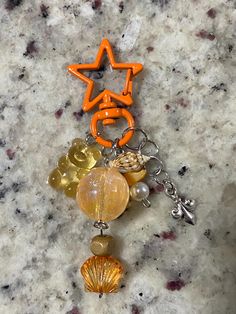 an orange star is attached to a keychain with seashells and charms