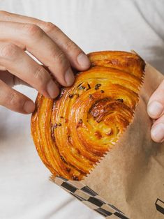 a person is holding a pastry in their left hand while they are eating it from a paper bag