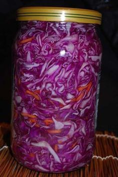 a jar filled with red cabbage sitting on top of a bamboo mat