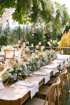 a long table with white flowers and greenery is set up for an outdoor dinner