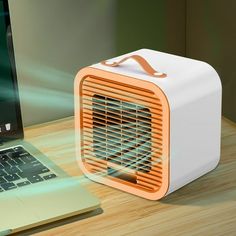 an orange and white portable air conditioner sitting next to a laptop on a desk