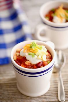 two white bowls filled with chili and sour cream