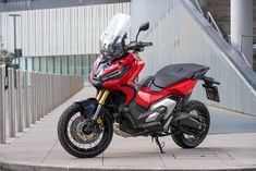 a red and black motorcycle parked in front of a building