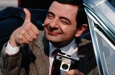 a man giving the thumbs up while holding an old camera