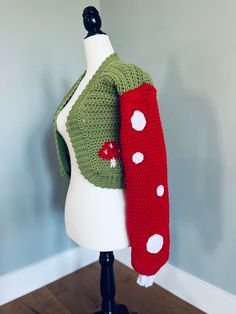 a white mannequin wearing a green and red sweater with polka dots on it