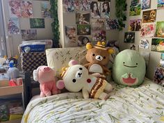 several stuffed animals sitting on top of a bed in a room filled with pictures and posters