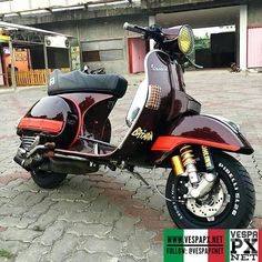 a red and black scooter parked in front of a building