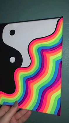 a person holding up a piece of art that looks like a rainbow wave with yin - yang on it