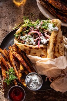 an assortment of food on a plate with sauces and pita bread next to it