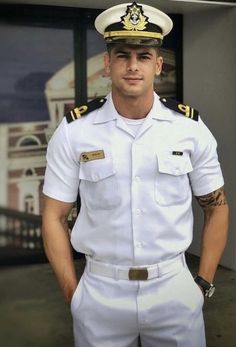 a man in a white uniform is posing for a photo with his hands on his hips