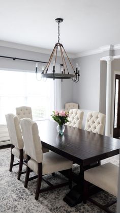 a dining room table with white chairs and a chandelier