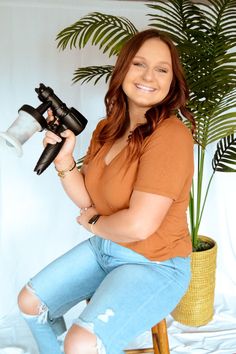 a woman sitting on a stool holding a blow dryer