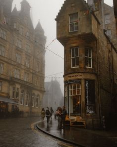 people are walking down the street in the rain