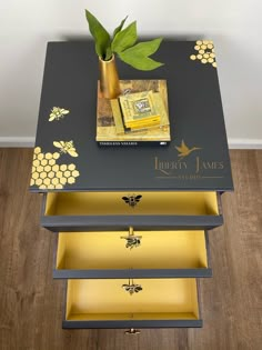 a black and gold side table with some books on it, next to a potted plant