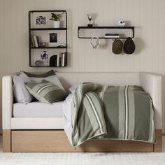 a bed with green and white striped comforter in front of a wall mounted shelf