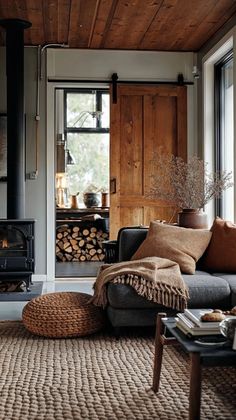 a living room filled with furniture and a fire place in front of a wooden wall