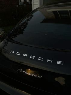 a black porsche parked in front of a house