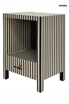 a black and white striped side table with one drawer open to show the bottom section