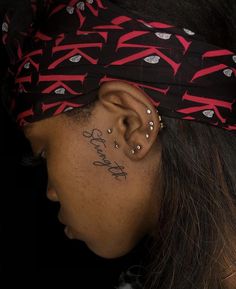 a close up of a person with a tattoo on their left side of her ear