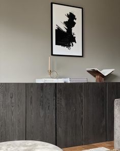 a living room with grey walls and wooden furniture in the corner, along with a framed black and white painting on the wall